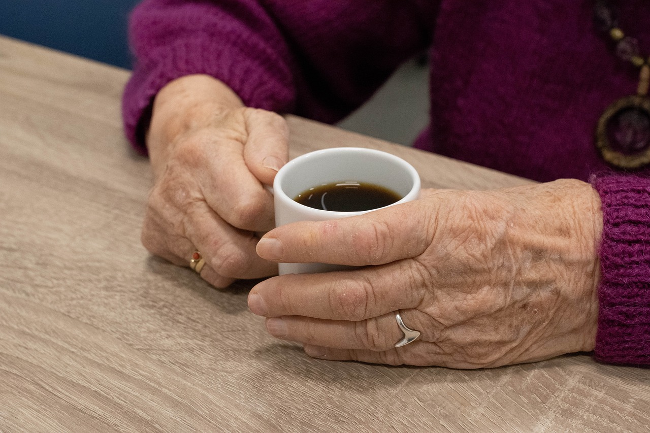 vanhan naisen kädet ja kahvikuppi